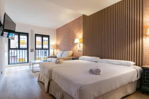 马德里H-A Aparthotel Hotel Quo的酒店客房设有两张床和电视。