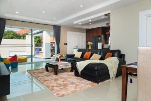 南芭堤雅CityHouse-OSCAR,pool villa 4Bedrooms-Jacuzzi-walking Street 10min的客厅配有黑色真皮沙发和桌子