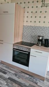 诺德豪森Zimmer的厨房配有白色橱柜和炉灶烤箱。