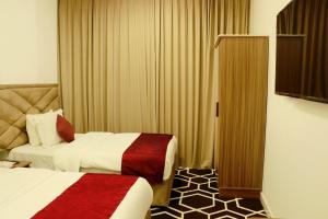 塞拉莱Alezz Suites Salalah的酒店客房设有两张床和电视。
