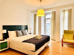里斯本Lucky Alameda Apartment的一间卧室配有一张大床和一张黄色椅子