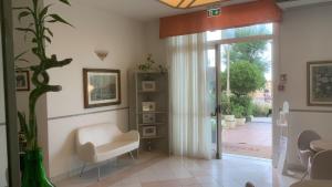 里米尼罗萨蒂酒店的客厅配有白色椅子和滑动玻璃门