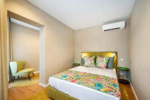 波尔图Casas do Porto - Ribeira Apartments的一间小卧室,配有一张床和一把椅子