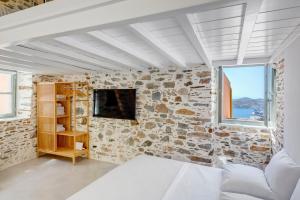 阿诺锡罗斯ArtdecoSyros Superior的一间卧室设有石墙、一张床和一台电视。