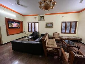 库塔兰Podhigai Garden Villa的客厅配有黑色沙发和椅子