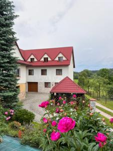 SkawaPokoje u Jasia i Małgosi的一座大房子,有红色的屋顶和粉红色的鲜花
