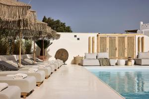 米克诺斯城Sharm Hotel Mykonos的毗邻度假酒店的带躺椅和椅子的游泳池