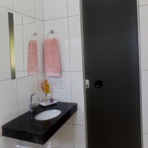 Sao Domingos de GoiasPousada Diadorim的浴室设有水槽、镜子和粉红色毛巾