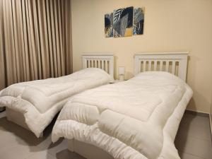 达曼Nesaj Villa的卧室内的两张床,配有白色棉被