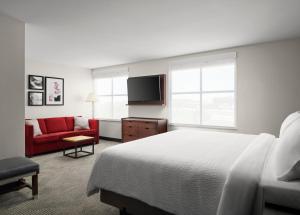 西切斯特辛辛那提北/西切斯特福朋喜来登酒店的酒店客房,配有一张床和一张红色的沙发