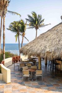 圣克鲁斯华特库Villas Coral Huatulco的一间设有桌椅的餐厅,并种植了棕榈树