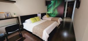 卡利Hotel Austral Suites的两张位于酒店客房的床,墙上挂着绿色画作