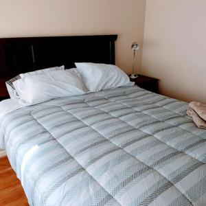 卡拉马Moderno Departamento en Calama的一张带黑色床头板和白色床单的白色床