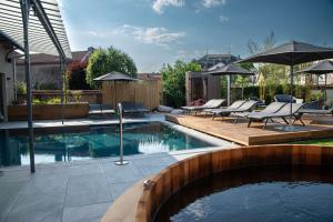 勒米尔蒙Best Western Premier Le Chapitre Hotel and Spa的后院的游泳池配有椅子和遮阳伞
