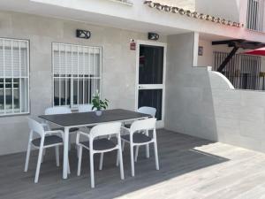 马拉加Malaga Chalet en Guadalmar的天井上配有一张黑桌和白色椅子