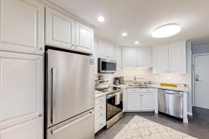 默特尔比奇Ocean Forest Villas E-308的白色的厨房配有白色橱柜和冰箱。