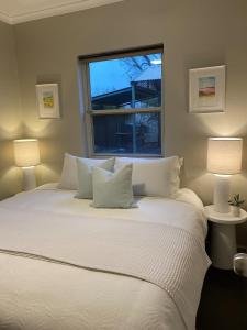AngastonAngaston Mews Apartments的一间卧室配有一张带两盏灯的大型白色床。