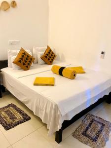 锡吉里亚斯吉利岩石边民宿的一张白色的床,上面有黄色和黑色的枕头