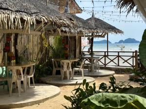 爱妮岛Panari Lodge El Nido的海滩上带桌椅的餐厅