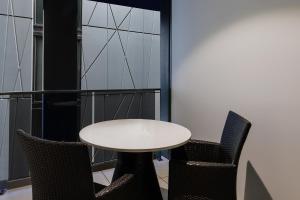 堪培拉Meriton Suites Canberra的客房内的一张白色桌子和两把椅子