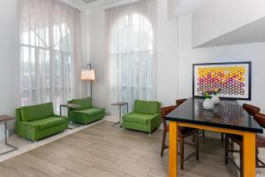 迈阿密迈阿密机场多拉地区快捷假日酒店的一间设有绿色椅子和绘画的等候室