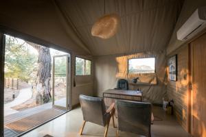 斯库库扎Nkuhlu Tented Camp的帐篷内的房间配有桌子和椅子