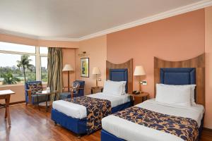 艾哈迈达巴德The Cama - A Sabarmati Riverfront Hotel的酒店客房设有两张床和窗户。