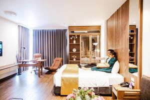 海防IRIS Hotel Hải Phòng的坐在酒店房间床上的女人