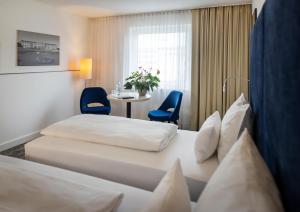 维也纳ARCOTEL Wimberger Wien的酒店客房带两张床和一张桌子以及椅子。