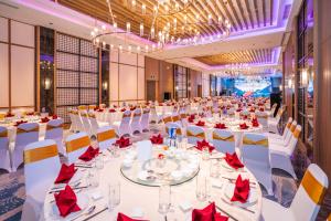 归仁Grand Hyams Hotel - Quy Nhon Beach的一个带白色桌子和红色餐巾的大型宴会厅