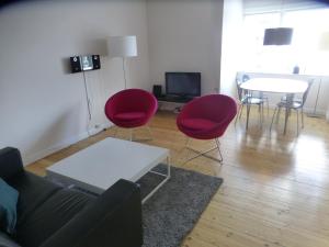 哥本哈根Christianshavn Apartments 536的客厅配有红色椅子和桌子