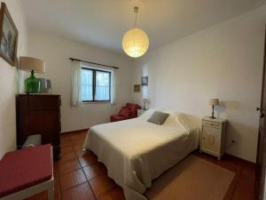 AreiasSanta Cruz Beach House的卧室配有白色的床和红色椅子