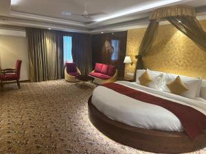 新德里Airport Hotel Ramhan Palace Mahipalpur的酒店客房带一张大床和椅子