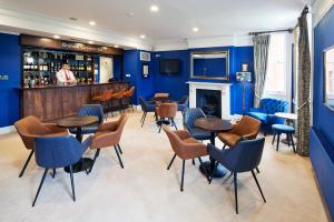 辛克斯顿Hinxton Hall Conference Centre的酒吧拥有蓝色的墙壁和桌椅