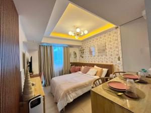 圣费尔南多Chic Hideaway at Azure North Bali Tower的一间卧室配有一张床和一张桌子及椅子
