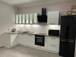 布鲁瓦Gîte « Les Basse des Grouets »的厨房配有白色橱柜和黑色冰箱。