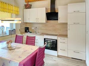 吕本瑙Ferienhaus Herz的厨房配有白色橱柜和一张带粉红色椅子的桌子