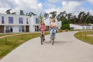 Hechtel-EkselPark Eksel的两名女孩骑着自行车沿着小路走