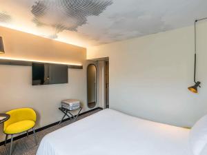 维拉德塞斯宜必思巴塞罗那维拉德坎斯机场酒店的一间卧室配有一张床、一张桌子和一张黄椅