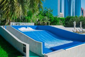 阿布扎比Radisson Blu Hotel & Resort, Abu Dhabi Corniche的拥有建筑的度假村内的一个蓝色海水游泳池