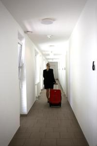 格拉茨Arbio I Urbanstay Serviced Studios & Apartments的带着红色手提箱沿着走廊走的女人
