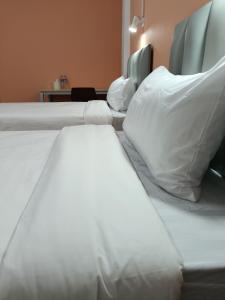 佛丕โรงแรม เดอะพีช / The Peach hotel的一间卧室配有两张带白色床单和枕头的床。
