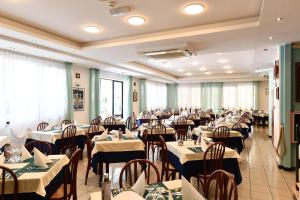 里米尼Hotel Criniera D'oro的大型用餐室配有桌椅