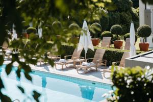 洛桑英格兰旅馆和公寓的游泳池旁的游泳池配有椅子和遮阳伞