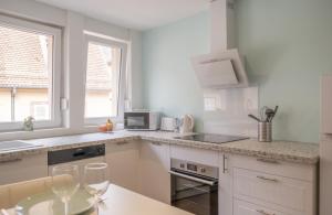 萨维尔纳Nouveau - Entre Terre et Mer - Centre Ville的厨房配有白色橱柜和酒杯桌子