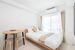 东京リアル大久保　Apartment Hotel的一间卧室配有一张床、一张桌子和一个窗户。
