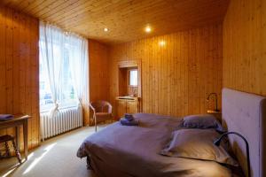 贝诺代Le Huic - Maison pour 9 avec jardin proche plage的木制客房的一间卧室配有一张床,设有窗户