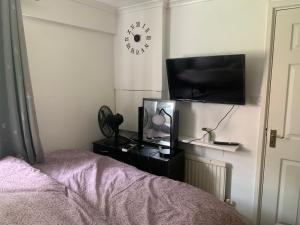 AddingtonLovely room in South London的一间卧室配有一张床、一台电视和一部时钟