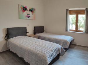 卡拉马塔Olive Stonehouses - Alkistis的卧室配有两张床,墙上挂着一幅画