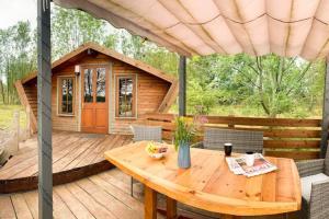 TuxfordWooden tiny house Glamping cabin with hot tub 1的木甲板,配有桌子和小屋